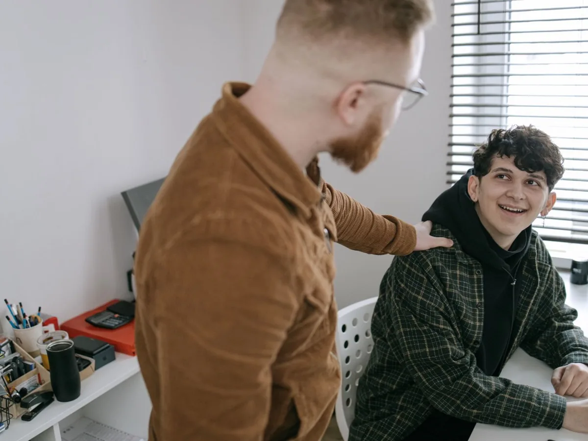 Twee mannen aan een bureau kijken samen naar een scherm.