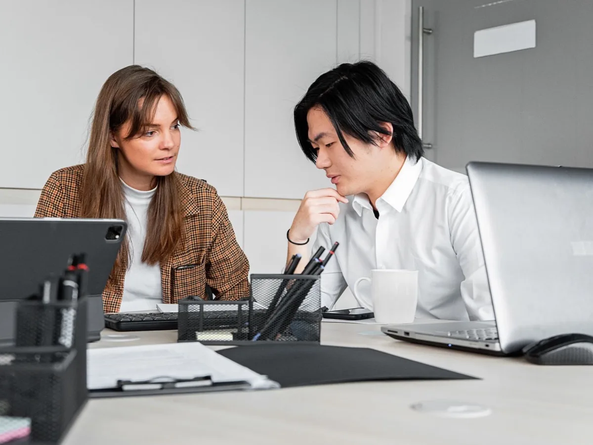 Twee collega's werken naast elkaar achter twee schermen.
