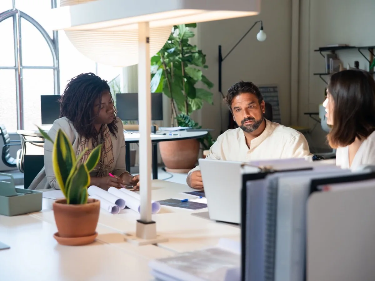 Drie collega's werken aan bureaus in een open kantoorruimte.